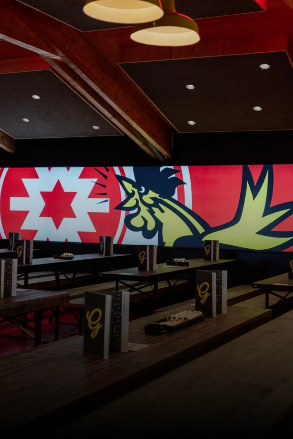 Banner mit leeren Bierbänken in einem Zelt, im Hintergrund sind die Logos von Wulle Bier und Göckelesmaier an der Zeltwand zu sehen.